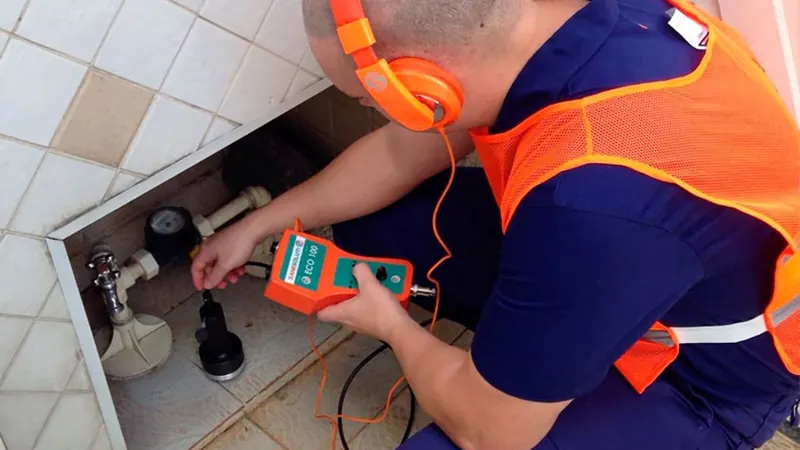 Técnico usando detector eletrônico para localizar vazamento em tubulação