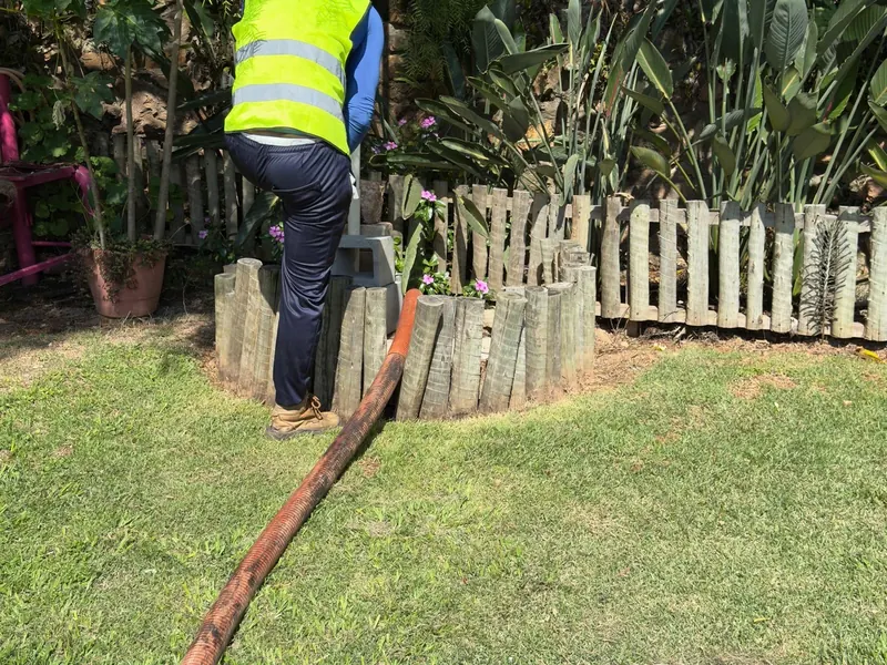 Técnico da Hidro Aqua fazendo limpeza de fossa em jardim residencial