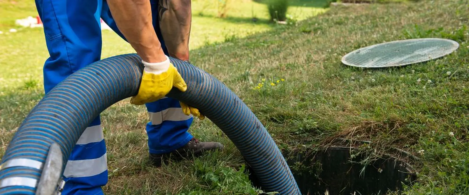 Técnico manuseando mangote de sucção durante a limpeza de uma fossa séptica